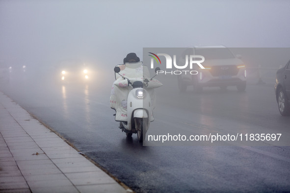 Citizens ride in heavy fog with visibility of less than 100 meters on a street in Hua County, Anyang, China, on December 5, 2024. 