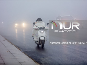 Citizens ride in heavy fog with visibility of less than 100 meters on a street in Hua County, Anyang, China, on December 5, 2024. (