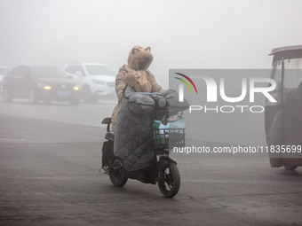 Cars travel in heavy fog with visibility of less than 100 meters on a street in Hua County, Anyang, China, on December 5, 2024. (