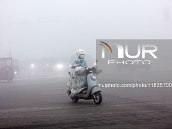 Citizens ride in heavy fog with visibility of less than 100 meters on a street in Hua County, Anyang, China, on December 5, 2024. (