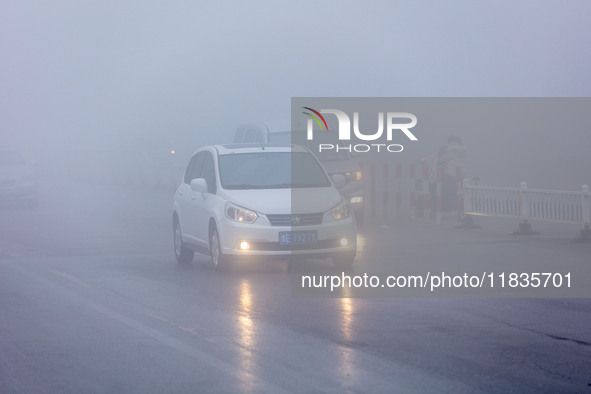 Cars travel in heavy fog with visibility of less than 100 meters on a street in Hua County, Anyang, China, on December 5, 2024. 