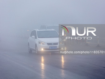 Cars travel in heavy fog with visibility of less than 100 meters on a street in Hua County, Anyang, China, on December 5, 2024. (