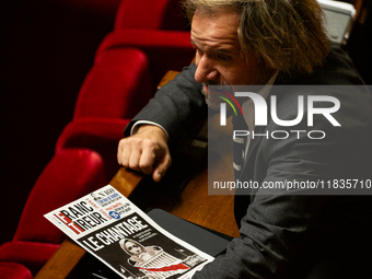 Thierry Sother, deputy of the Socialistes et Apparentes group, holds a newspaper with the headline ''Blackmail'' during the session examinin...