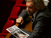 Thierry Sother, deputy of the Socialistes et Apparentes group, holds a newspaper with the headline ''Blackmail'' during the session examinin...