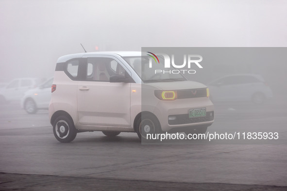 Cars operate in heavy fog with visibility of less than 100 meters on a street in Hua County, Anyang city, central China's Henan province, on...