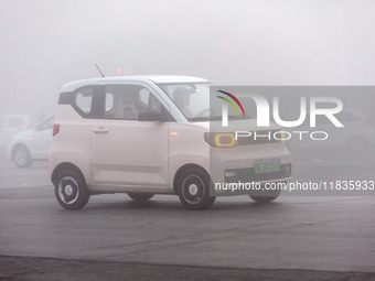 Cars operate in heavy fog with visibility of less than 100 meters on a street in Hua County, Anyang city, central China's Henan province, on...