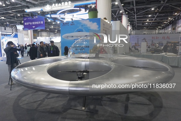 Visitors look at a manned flying saucer electric vertical take-off and landing vehicle (eVTOL) at the Zhejiang International Intelligent Tra...