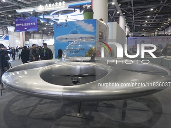 Visitors look at a manned flying saucer electric vertical take-off and landing vehicle (eVTOL) at the Zhejiang International Intelligent Tra...