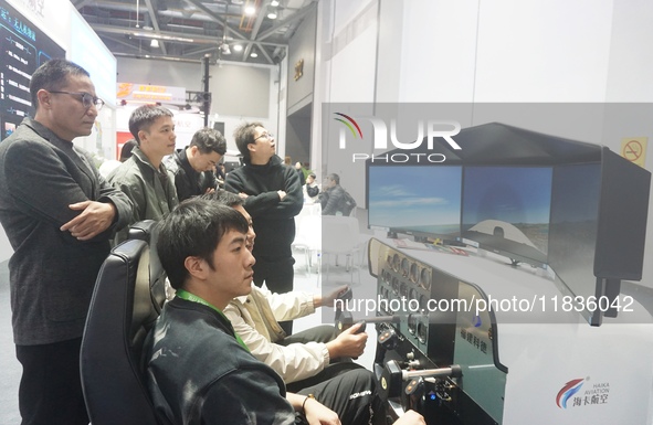 Visitors experience flying on a flight simulator at the Zhejiang International Intelligent Transportation Industry Expo in Hangzhou, China,...