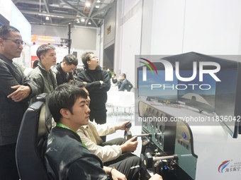 Visitors experience flying on a flight simulator at the Zhejiang International Intelligent Transportation Industry Expo in Hangzhou, China,...