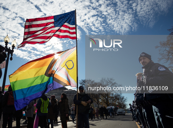 A man with enormous American and pride flags stands in front of a Capitol Police lines during demonstrations at the Supreme Court over gende...