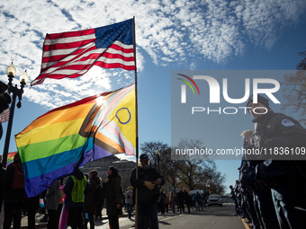 A man with enormous American and pride flags stands in front of a Capitol Police lines during demonstrations at the Supreme Court over gende...