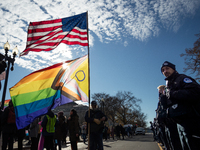 A man with enormous American and pride flags stands in front of a Capitol Police lines during demonstrations at the Supreme Court over gende...