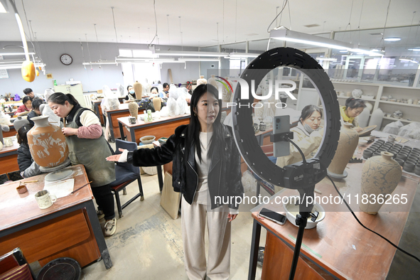 A staff member of a ceramic company helps job seekers understand the working environment of the company through a webcast in Handan, China,...