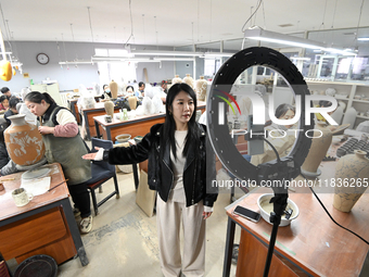 A staff member of a ceramic company helps job seekers understand the working environment of the company through a webcast in Handan, China,...