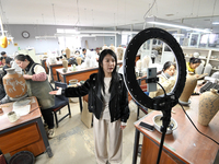 A staff member of a ceramic company helps job seekers understand the working environment of the company through a webcast in Handan, China,...