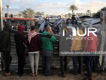 Palestinians inspect the damage in the aftermath of an Israeli strike on a tent camp in Khan Younis, Gaza Strip, on December 5, 2024, amid t...