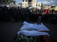 People gather near the body of a Palestinian killed in an Israeli strike at Nasser hospital in Khan Younis, Gaza Strip, on December 5, 2024....