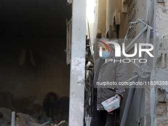 People stand on the rubble of a building after an Israeli strike in Nuseirat, Gaza Strip, on December 5, 2024, as the war between Israel and...