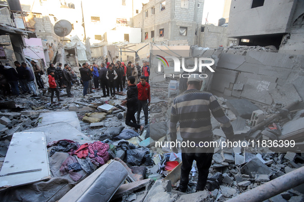 People stand on the rubble of a building after an Israeli strike in Nuseirat, Gaza Strip, on December 5, 2024, as the war between Israel and...