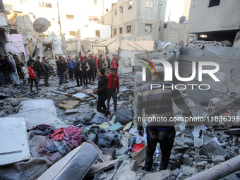 People stand on the rubble of a building after an Israeli strike in Nuseirat, Gaza Strip, on December 5, 2024, as the war between Israel and...