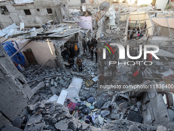 People stand on the rubble of a building after an Israeli strike in Nuseirat, Gaza Strip, on December 5, 2024, as the war between Israel and...