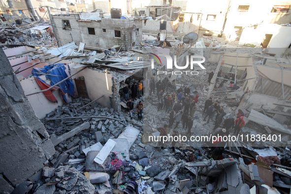 People stand on the rubble of a building after an Israeli strike in Nuseirat, Gaza Strip, on December 5, 2024, as the war between Israel and...