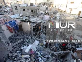 People stand on the rubble of a building after an Israeli strike in Nuseirat, Gaza Strip, on December 5, 2024, as the war between Israel and...