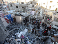 People stand on the rubble of a building after an Israeli strike in Nuseirat, Gaza Strip, on December 5, 2024, as the war between Israel and...