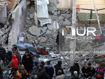 People stand on the rubble of a building after an Israeli strike in Nuseirat, Gaza Strip, on December 5, 2024, as the war between Israel and...