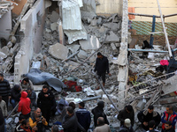 People stand on the rubble of a building after an Israeli strike in Nuseirat, Gaza Strip, on December 5, 2024, as the war between Israel and...