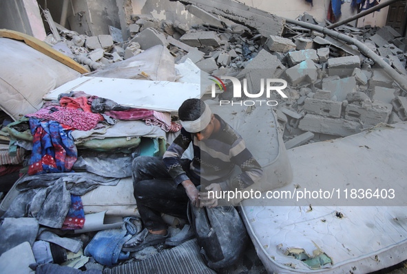 People stand on the rubble of a building after an Israeli strike in Nuseirat, Gaza Strip, on December 5, 2024, as the war between Israel and...