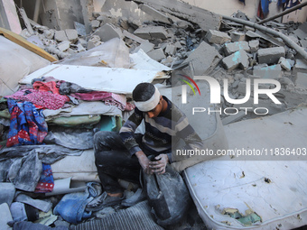 People stand on the rubble of a building after an Israeli strike in Nuseirat, Gaza Strip, on December 5, 2024, as the war between Israel and...