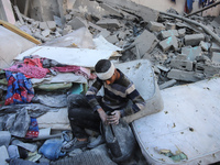 People stand on the rubble of a building after an Israeli strike in Nuseirat, Gaza Strip, on December 5, 2024, as the war between Israel and...