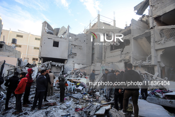 People stand on the rubble of a building after an Israeli strike in Nuseirat, Gaza Strip, on December 5, 2024, as the war between Israel and...