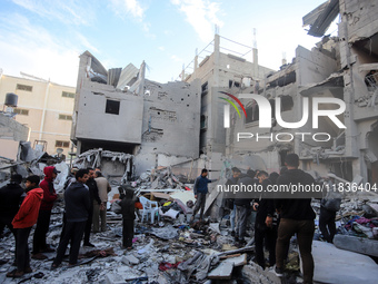 People stand on the rubble of a building after an Israeli strike in Nuseirat, Gaza Strip, on December 5, 2024, as the war between Israel and...