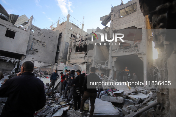 People stand on the rubble of a building after an Israeli strike in Nuseirat, Gaza Strip, on December 5, 2024, as the war between Israel and...