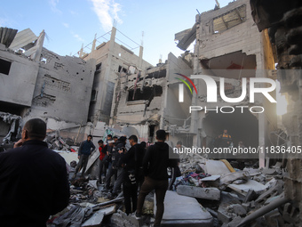 People stand on the rubble of a building after an Israeli strike in Nuseirat, Gaza Strip, on December 5, 2024, as the war between Israel and...