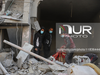 People stand on the rubble of a building after an Israeli strike in Nuseirat, Gaza Strip, on December 5, 2024, as the war between Israel and...