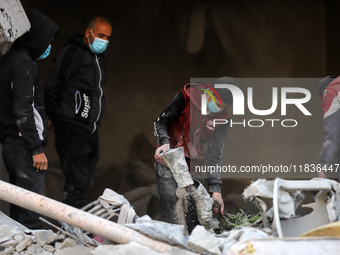 People stand on the rubble of a building after an Israeli strike in Nuseirat, Gaza Strip, on December 5, 2024, as the war between Israel and...