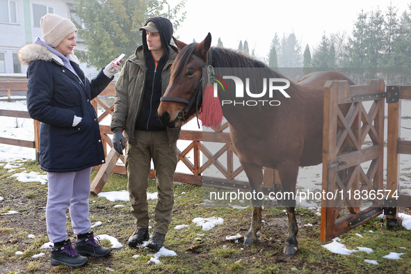 In Kosiv, Ukraine, on December 2, 2024, a worker speaks to a journalist about the Hutsul pony, also known as the Hucul pony or Carpathian po...