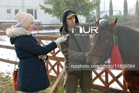 In Kosiv, Ukraine, on December 2, 2024, a worker speaks to a journalist about the Hutsul pony, also known as the Hucul pony or Carpathian po...