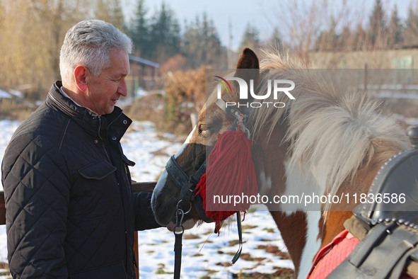 In Kosiv, Ukraine, on December 2, 2024, the Director of the Hutsulshchyna National Nature Park, Yurii Stefurak, pets a Hutsul pony, also kno...