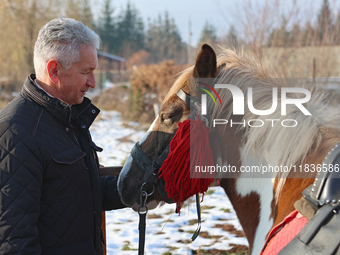 In Kosiv, Ukraine, on December 2, 2024, the Director of the Hutsulshchyna National Nature Park, Yurii Stefurak, pets a Hutsul pony, also kno...