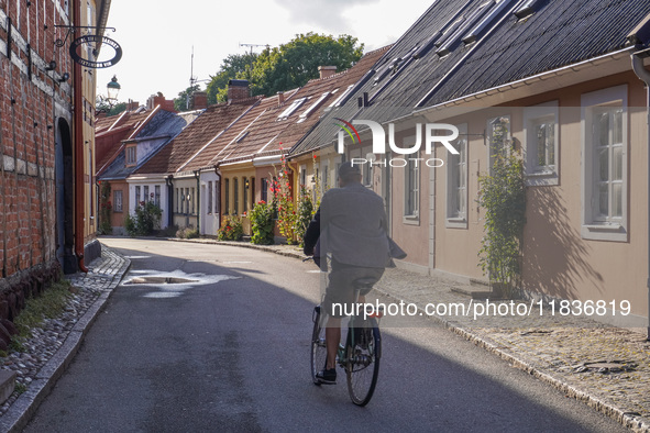 A man cycles on a bicycle along the houses in Ystad, Sweden, on August 4, 2024. 