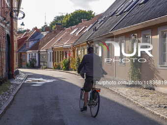 A man cycles on a bicycle along the houses in Ystad, Sweden, on August 4, 2024. (