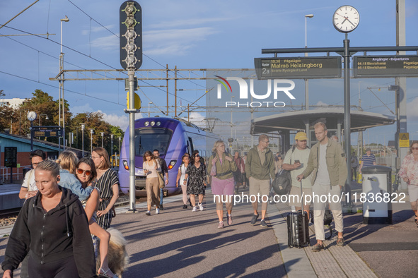 People get off the train on the platform of the train station in Ystad, Sweden, on August 4, 2024. 