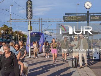 People get off the train on the platform of the train station in Ystad, Sweden, on August 4, 2024. (