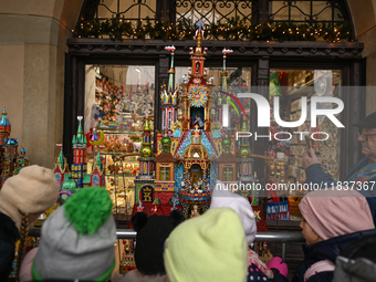 KRAKOW, POLAND - DECEMBER 05:
Visitors, tourists, and locals gather in Krakow's Main Square, capturing photos of the detailed handcrafted Na...