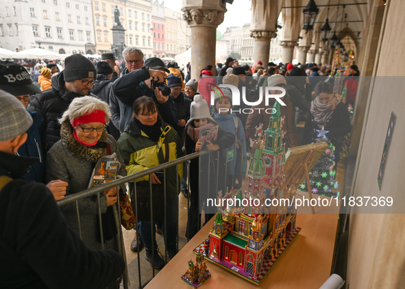 KRAKOW, POLAND - DECEMBER 05:
Visitors, tourists, and locals gather in Krakow's Main Square, capturing photos of the detailed handcrafted Na...